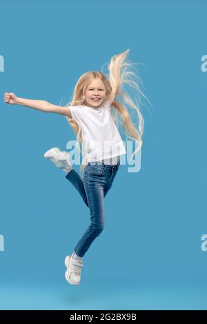 Cheerful little girl jumping in photo studio