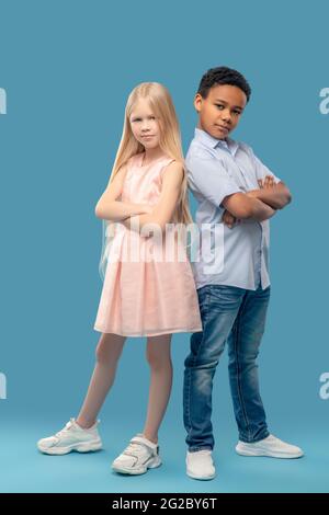 Caucasian girl and darkskinned boy standing with folded hands Stock Photo