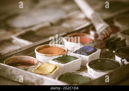 Old paint box with aquarelle watercolors with brush, antique vintage style, desaturated colours, closeup Stock Photo