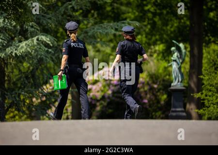 Hanover, Germany. 10th June, 2021. Police forces walk through the Stöcken city cemetery before the start of the funeral of a murder victim. On 03.06.2021 there was an altercation between occupants of two cars on the open road in Hanover, in the course of which a man was killed. Credit: Moritz Frankenberg/dpa/Alamy Live News Stock Photo