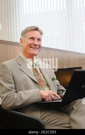 Businessman working at a laptop in a railway station lounge in England. Stock Photo