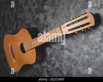 Acoustic guitar on the grey textured background. Old vintage headstock close up, selective focus Stock Photo