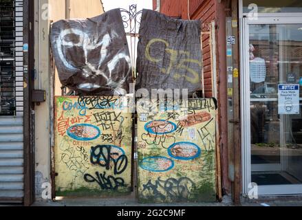A fence covered in fabric & wood that has become an urban collage of graffiti, stickers and tags. In Coney Island Brooklyn, New York. Stock Photo