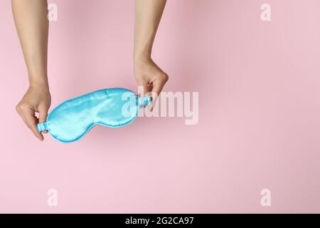 Female hands hold sleep mask on pink background Stock Photo