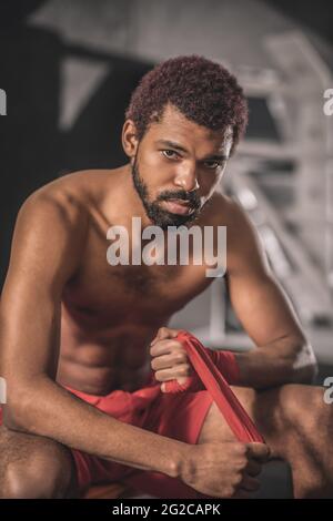 Dark-skinned young sportsman in a gym getting ready for the workout Stock Photo
