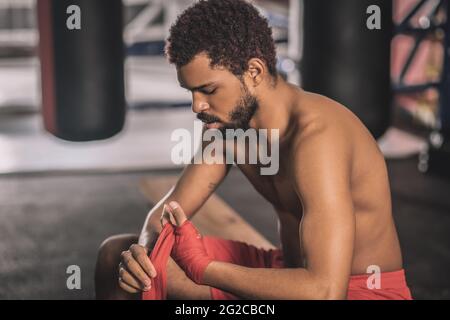 Dark-skinned athlete typing his hands with a red bandage Stock Photo