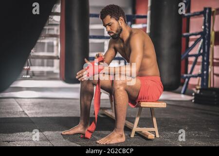 Dark-skinned athlete typing his hands with a red bandage Stock Photo