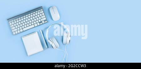 Wide banner on a light blue background, flat layout, keyboard, headphones, notebook, smartphone. Concept - home office, online education, webinars Stock Photo