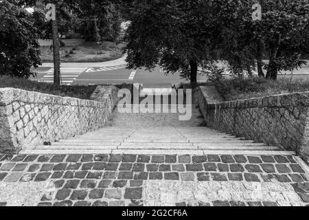 Fence and staircase made of granite stones. A cobbled area with a stone cobblestone fence. Observation deck in the city park. Black and white photo Stock Photo