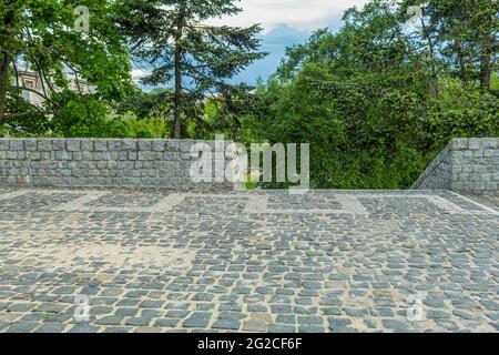 Fence and staircase made of granite stones. A cobbled area with a stone cobblestone fence. Observation deck in the city park Stock Photo