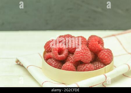 Raspberries are fresh and juicy on a wooden background. Ripe raspberries in a basket on a wooden table. Close-up, background with space for text. Harv Stock Photo