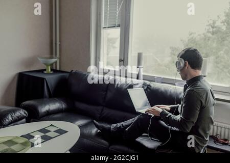 Man sitting on sofa and using laptop Stock Photo