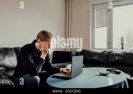 Man sitting on sofa and using laptop Stock Photo