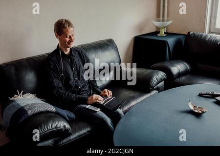 Man sitting on sofa and using Braille keyboard Stock Photo