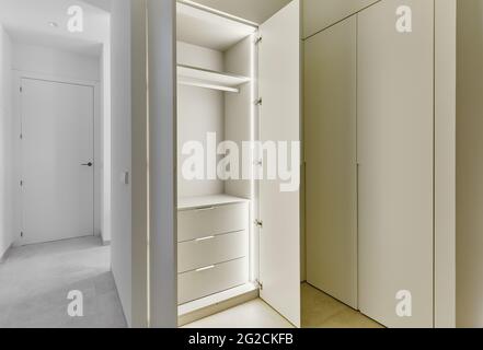 Opened door of light up white wooden fashionable built-in wardrobe, no people. Interior design ideas, comfort, luxury concept Stock Photo