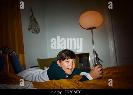 Boy on bed using digital tablet Stock Photo
