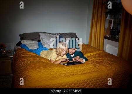 Boys using digital tablet on bed Stock Photo