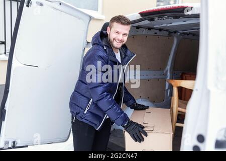 Smiling man unloading boxes from van Stock Photo