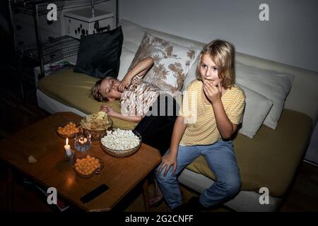 Brothers snacking on sofa Stock Photo