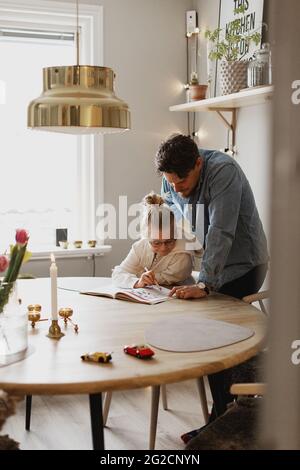 Father helping daughter doing homework Stock Photo