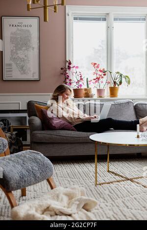Woman on sofa using laptop Stock Photo
