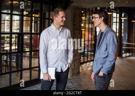 Two men standing in modern interior and discussing Stock Photo