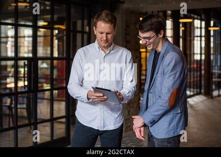 Two men standing in modern interior and discussing Stock Photo
