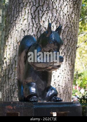 A metal, wrought iron black squirrel sculpture eating an acorn at a park in Brooklyn, New York. Stock Photo