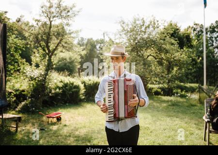 Man playing accordion in garden Stock Photo