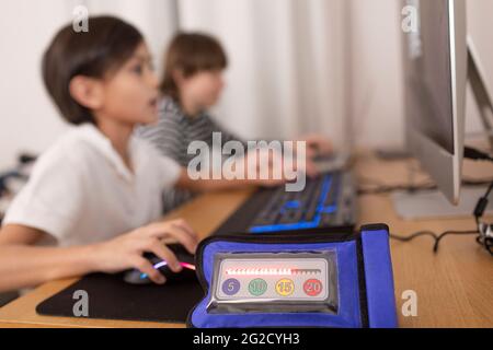 Close-up of timer, boys using computers on background Stock Photo
