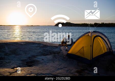 Couple camping at lake and various Internet services icons Stock Photo