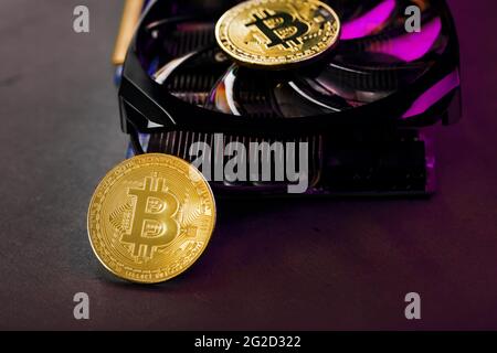 On the fans of a powerful video card, the coins of the Bitcoin cryptocurrency with a red backlight are displayed.The concept of mining and mining of c Stock Photo