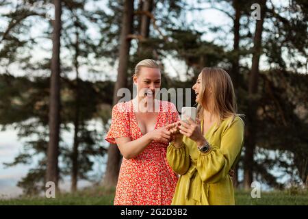 Smiling female friends using smart phone Stock Photo