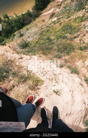 Two people standing on the cliff by the water, first person view, summer vacation concept Stock Photo