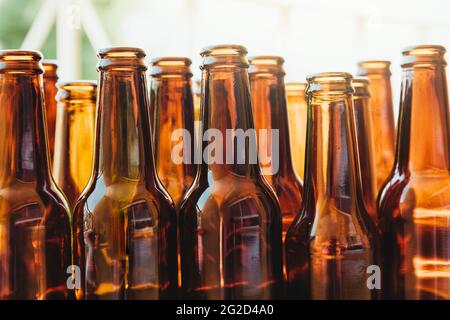 Several brown glass bottles seen from a low angle. A lot of light enters behind the bottles. Stock Photo