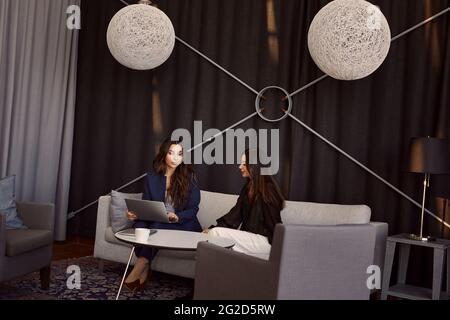 Female coworkers sitting on sofa Stock Photo