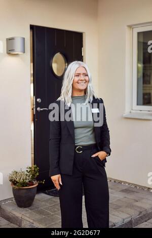 Smiling estate agent standing in front of house Stock Photo
