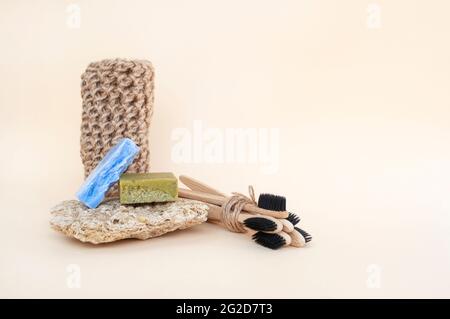 Zero waste bathroom accessories - toothbrushes, natural soap and knit twine scrubber on a beige background. Sustainable lifestyle concept. Stock Photo