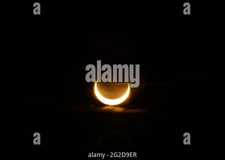 Ottawa, Canada. June 10, 2021: A partial solar eclipse is seen over Parliament Hill in Ottawa, Canada - Thursday, June 10, 2021. The annular or 'ring of fire' solar eclipse is only visible to some people in Greenland, Northern Russia, and Canada. Here, the sun is seen at its maximum eclipse point, less than 3 degrees above the horizon in Ottawa. Credit: George Ross/Alamy Live News Stock Photo