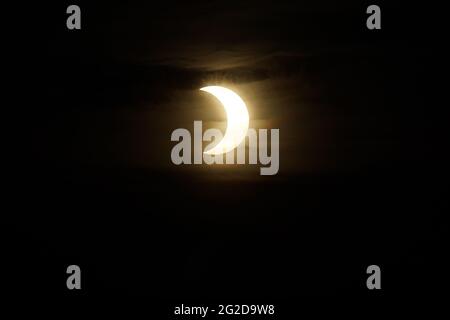 Ottawa, Canada. June 10, 2021: A partial solar eclipse is seen over Parliament Hill in Ottawa, Canada - Thursday, June 10, 2021. The annular or 'ring of fire' solar eclipse is only visible to some people in Greenland, Northern Russia, and Canada. In Canada's National Capital Region, the sun was less than 3 degrees above the horizon at the peak of the eclipse. Credit: George Ross/Alamy Live News Stock Photo