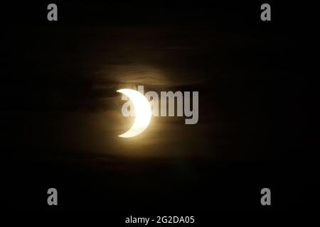 Ottawa, Canada. June 10, 2021: A partial solar eclipse is seen over Parliament Hill in Ottawa, Canada - Thursday, June 10, 2021. The annular or 'ring of fire' solar eclipse is only visible to some people in Greenland, Northern Russia, and Canada. In Canada's National Capital Region, the sun was less than 3 degrees above the horizon at the peak of the eclipse. Credit: George Ross/Alamy Live News Stock Photo