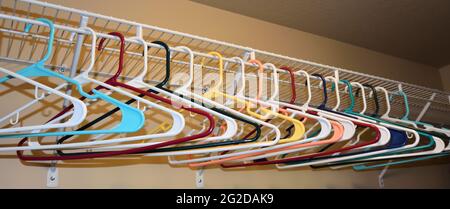 Colorful empty clothes hangers aligned in a closet. Stock Photo