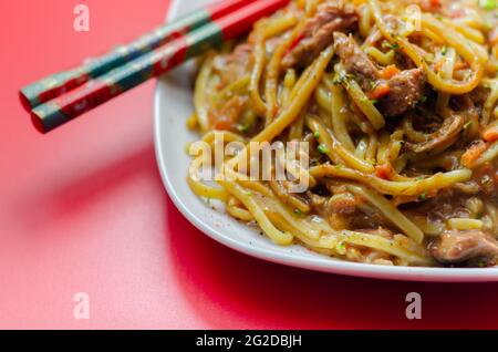 Cooked free range egg noodles with shredded duck in a savoury plum, ginger, chilli and garlic sauce with onions, carrots, pak choi, water chestnuts, o Stock Photo