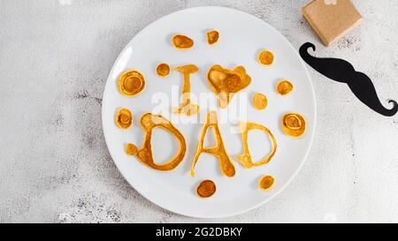 Celebrating Father's Day. Breakfast: pancakes in form of congratulations - I love dad , and coffee mug and . copy space. Stock Photo