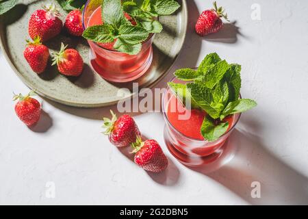 Fresh strawberry juice, cold summer berry cocktail with mint in glasses, healthy natural food, harsh lighting Stock Photo