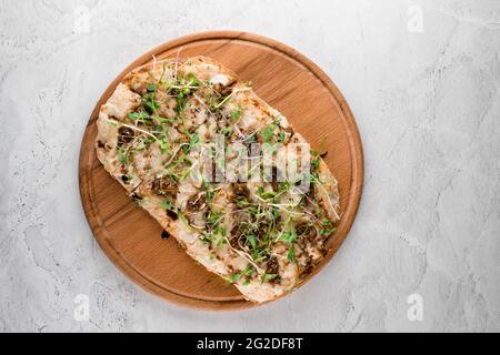 Italian pinsa romana with french escargot grape snails on white background. Pinsa with snail, cheese, microgreen. Italian gourmet cuisine. Stock Photo