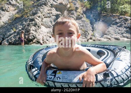 A kid floats down the rapids on a river in France on a rubber ring. Stock Photo