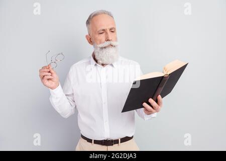 Photo of aged man concentrated focused read story novel book hold glasses isolated over grey color background Stock Photo