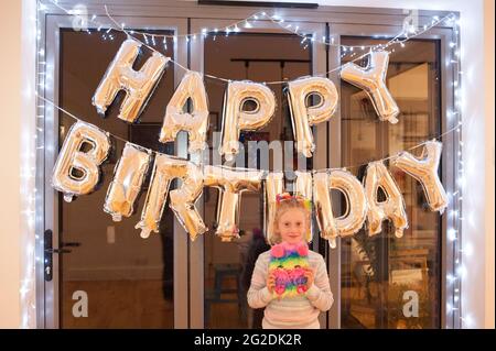 A mother holds out a birthday cake for a little girl on her 7th birthday Stock Photo