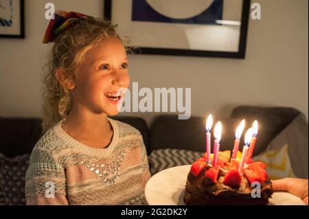 A mother holds out a birthday cake for a little girl on her 7th birthday Stock Photo